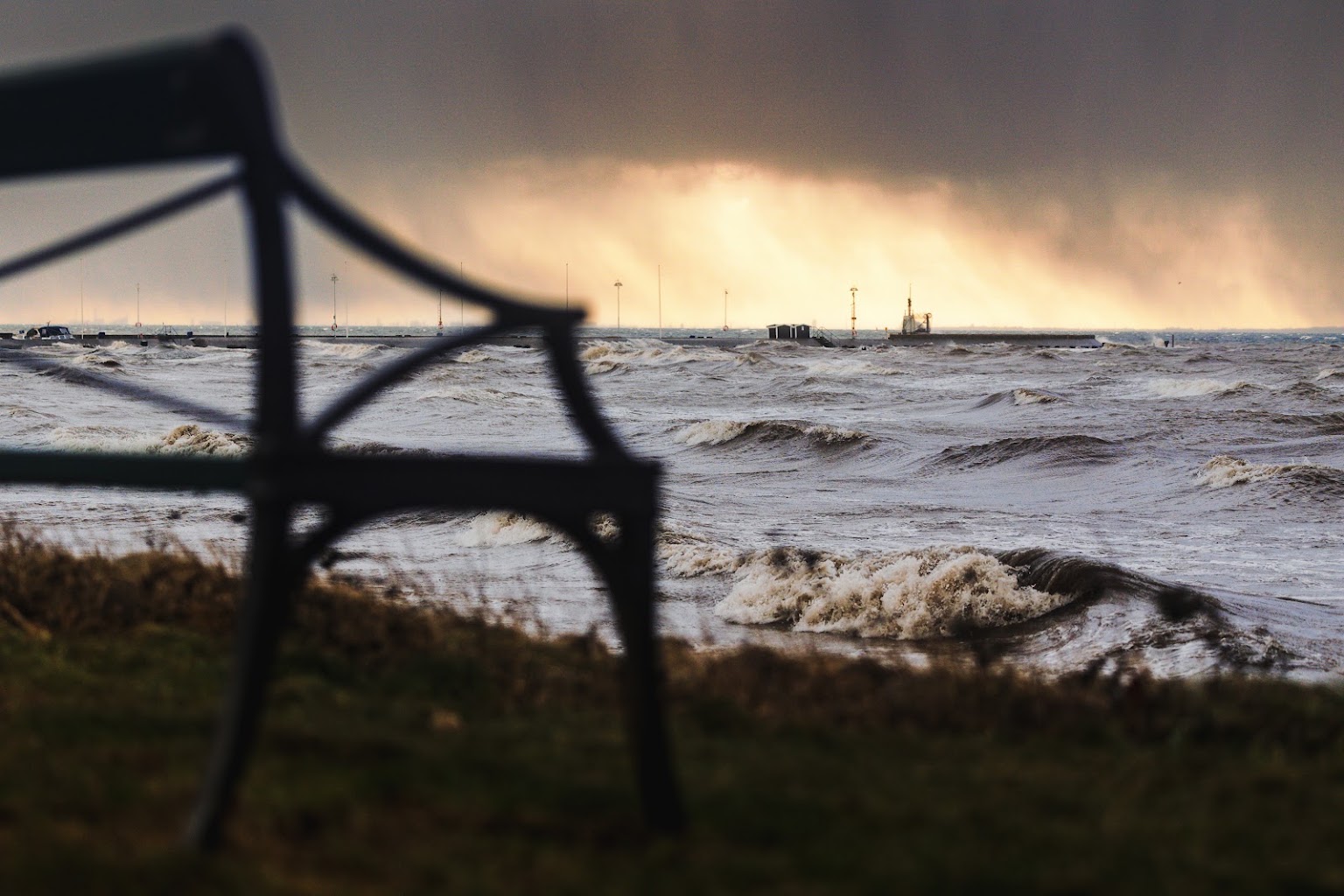 En bänk i siluett mot stormvågorna