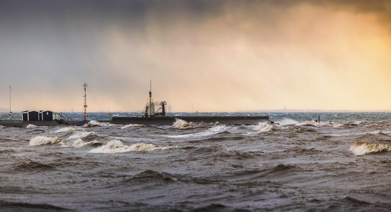 Stormvågor över Öresund i gyllene ljus under stormen Pia